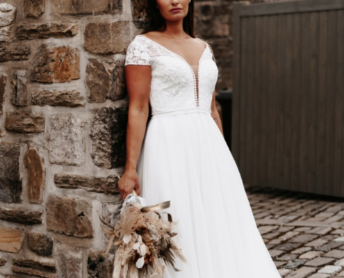 Bohemian style wedding dress in ivory with plunge neckline and delicate lace detail.