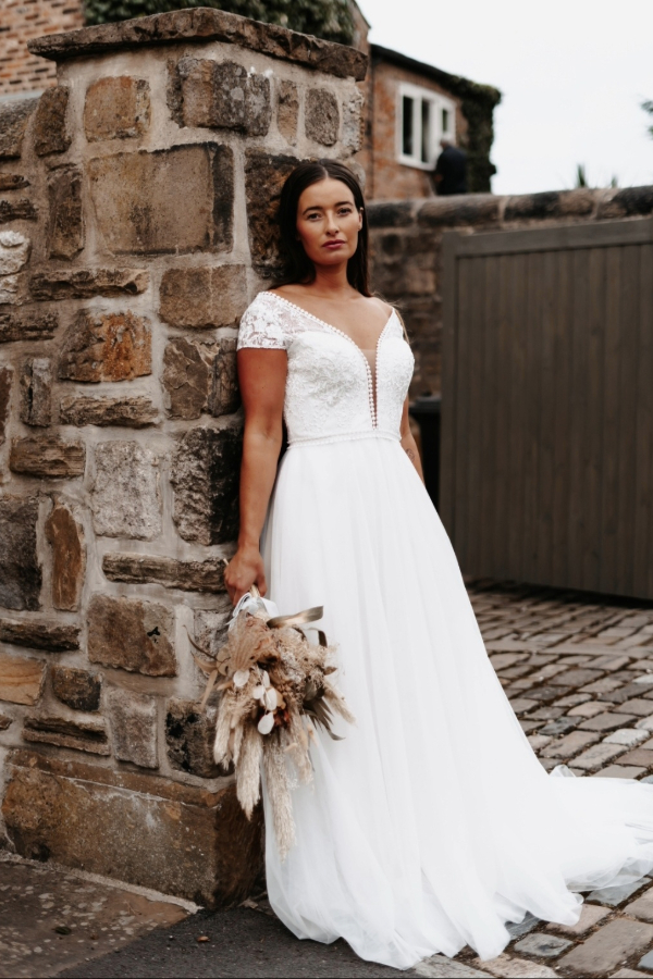 Bohemian style wedding dress in ivory with plunge neckline and delicate lace detail.